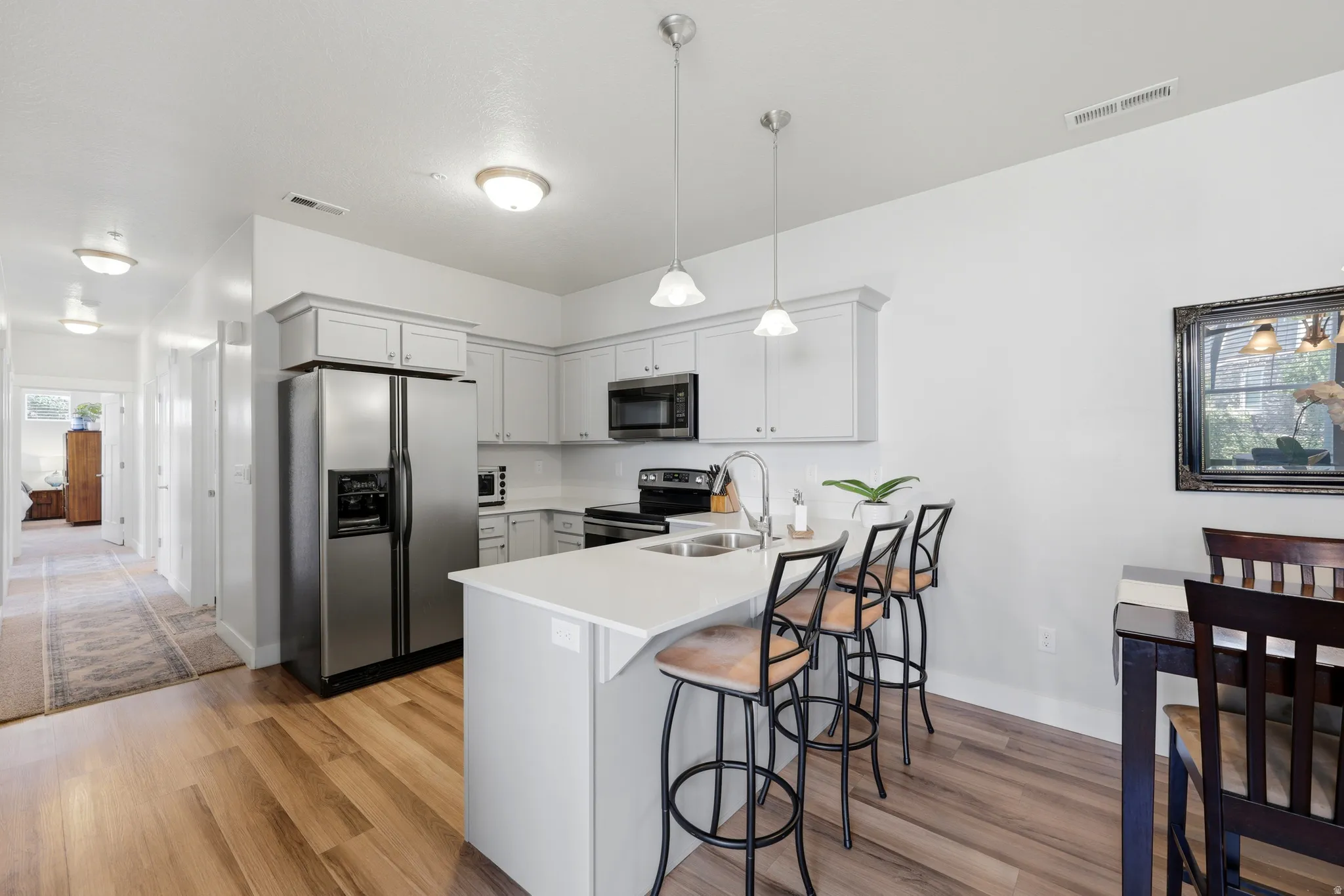 Modern kitchen featuring a white cabinetry layout with a substantial island countertop, stainless steel side-by-side refrigerator with ice and water dispensers, and black electric range