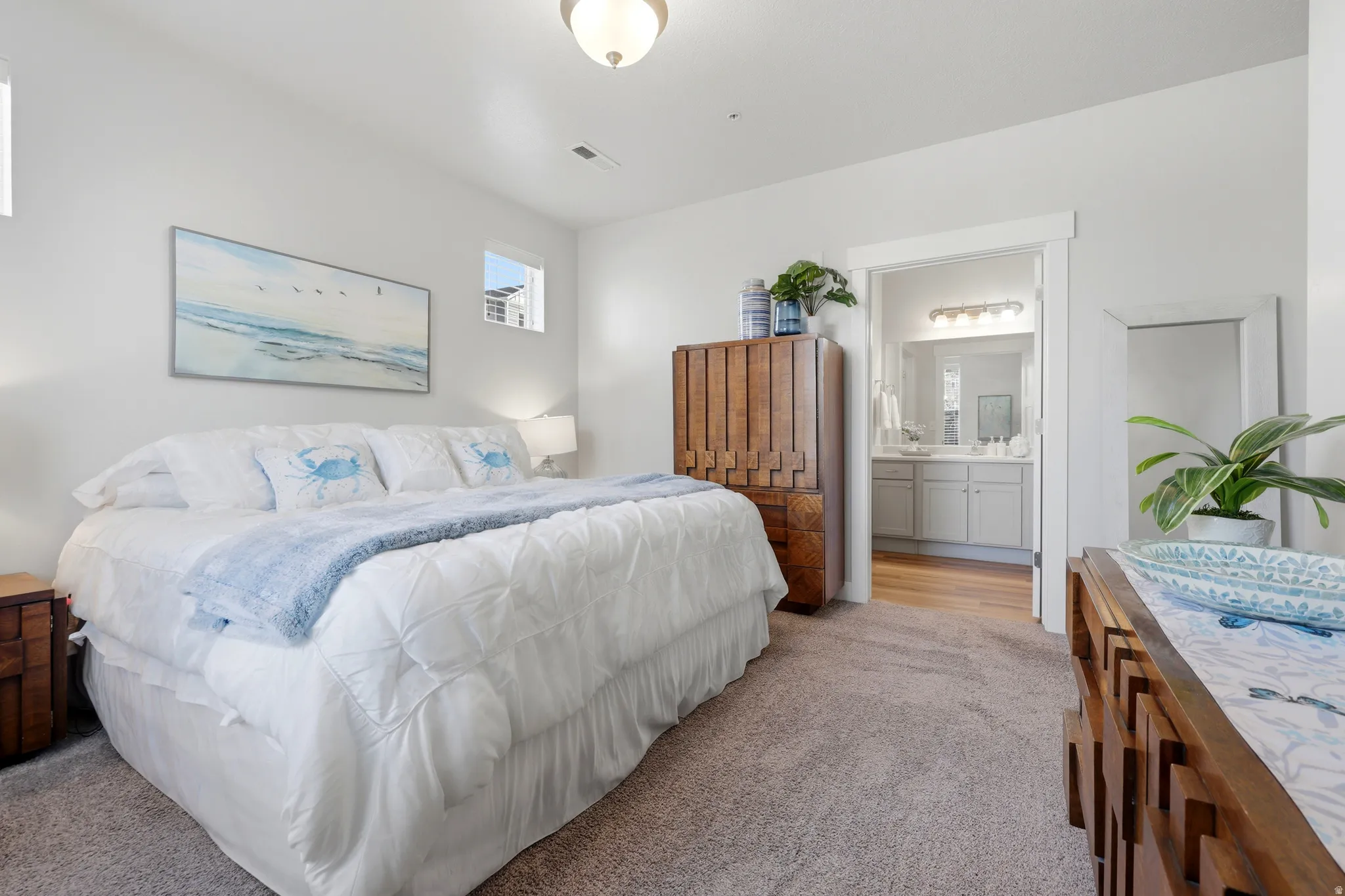 Spacious primary bedroom featuring a queen-size bed with white bedding, dual nightstands with wood-finish construction, and soft ambient lighting