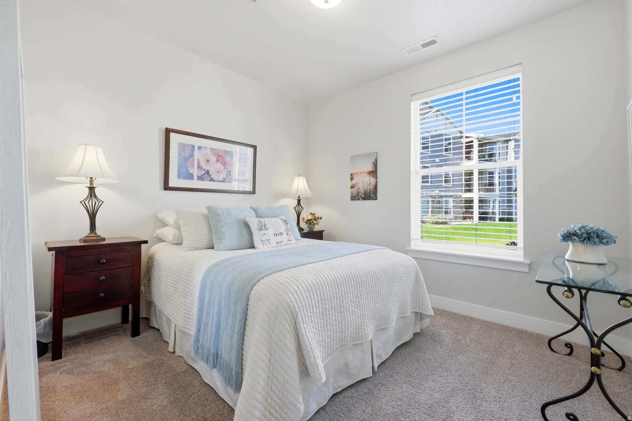 Serene bedroom retreat featuring a queen bed with crisp linens, soft blue accents, and layered bedding