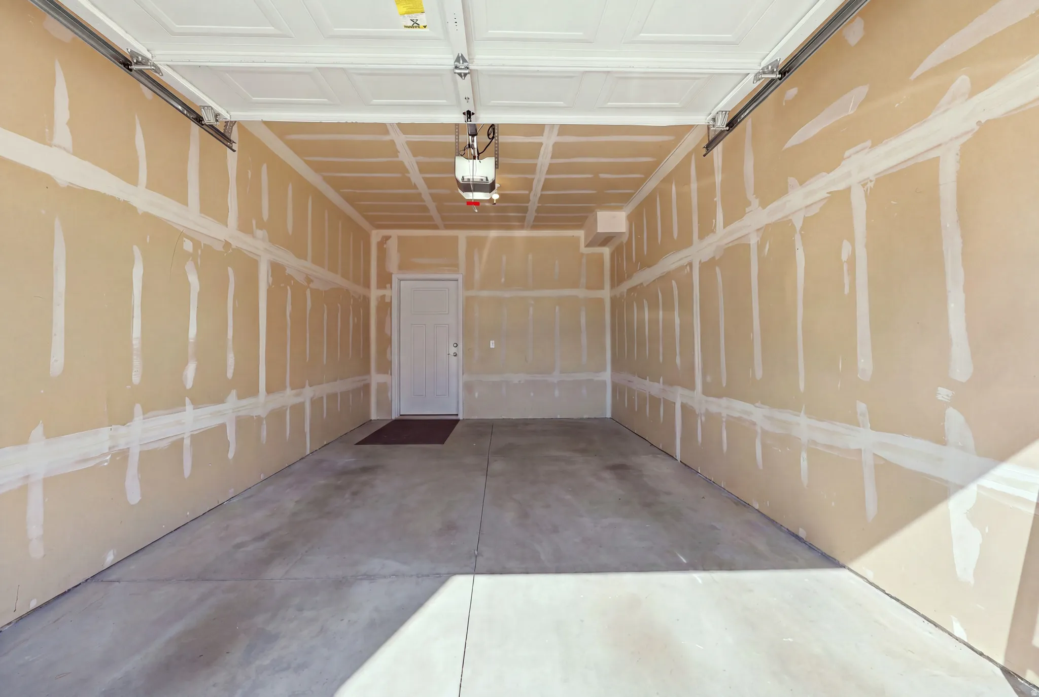 Spacious garage interior featuring a concrete floor, an overhead garage door, and a paneled white ceiling
