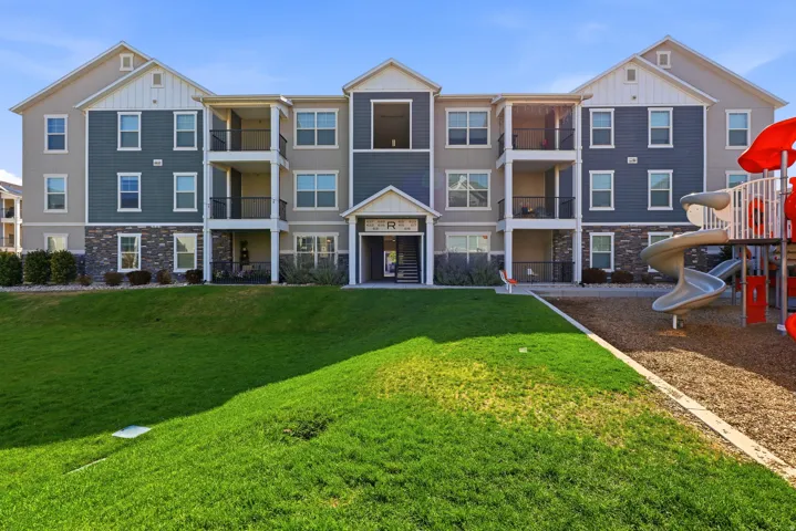 Multi-story apartment building featuring gabled rooflines, balconies, and stone veneer accents