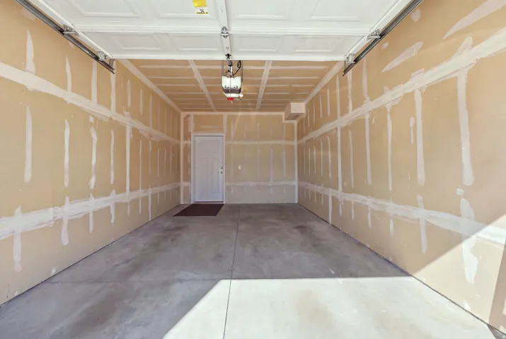 Spacious garage interior featuring a concrete floor, an overhead garage door, and a paneled white ceiling