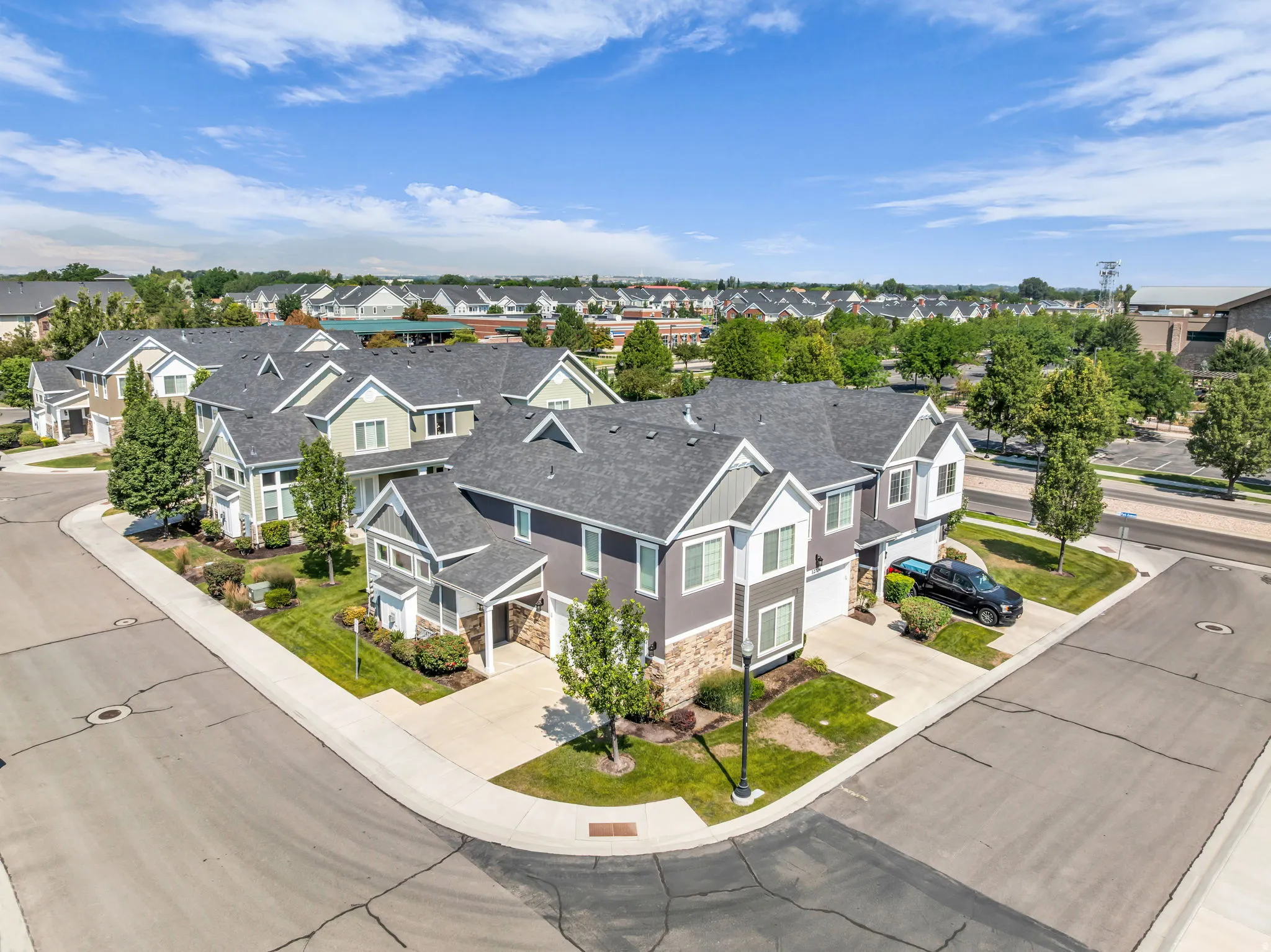 Modern residential development featuring multi-story homes with gabled roofs, stone accents, and light-colored siding