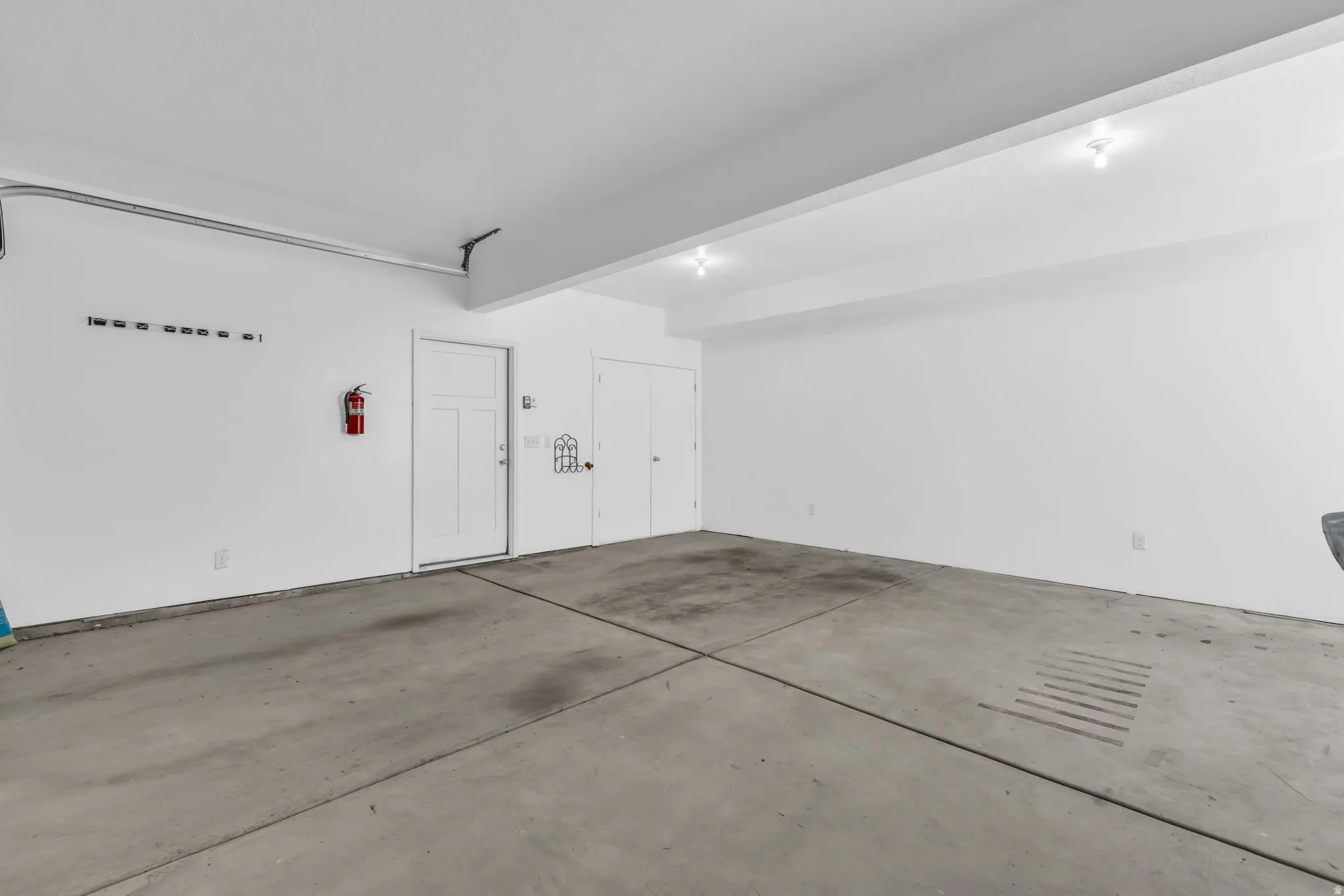 Spacious garage featuring concrete flooring, crisp white walls, recessed ceiling lighting, and a paneled interior door