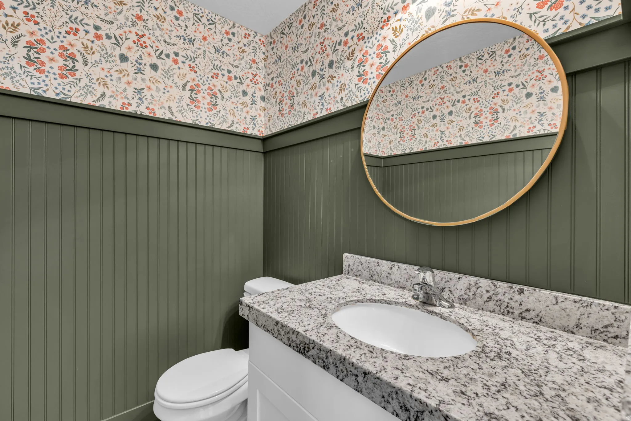Vanity featuring a white undermount sink, speckled countertop, and chrome faucet