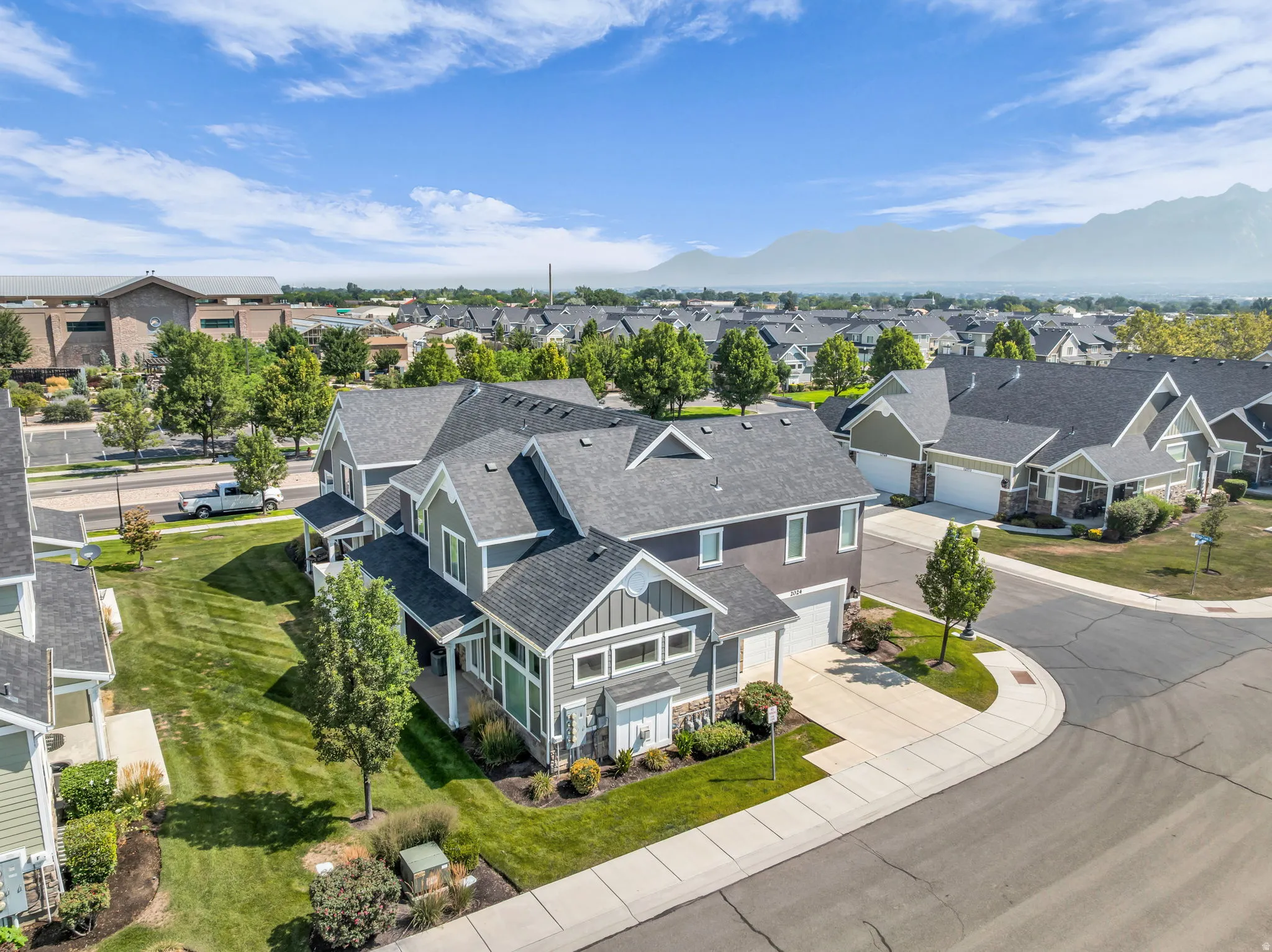 Contemporary multi-story residence featuring a dark gray roof, light gray siding, and stone accents