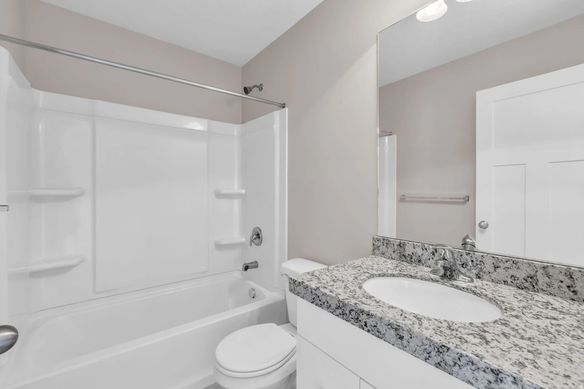 Bathroom featuring a vanity with an undermount sink, a stone countertop, chrome fixtures, and a shower/tub combination with an integrated shelving unit