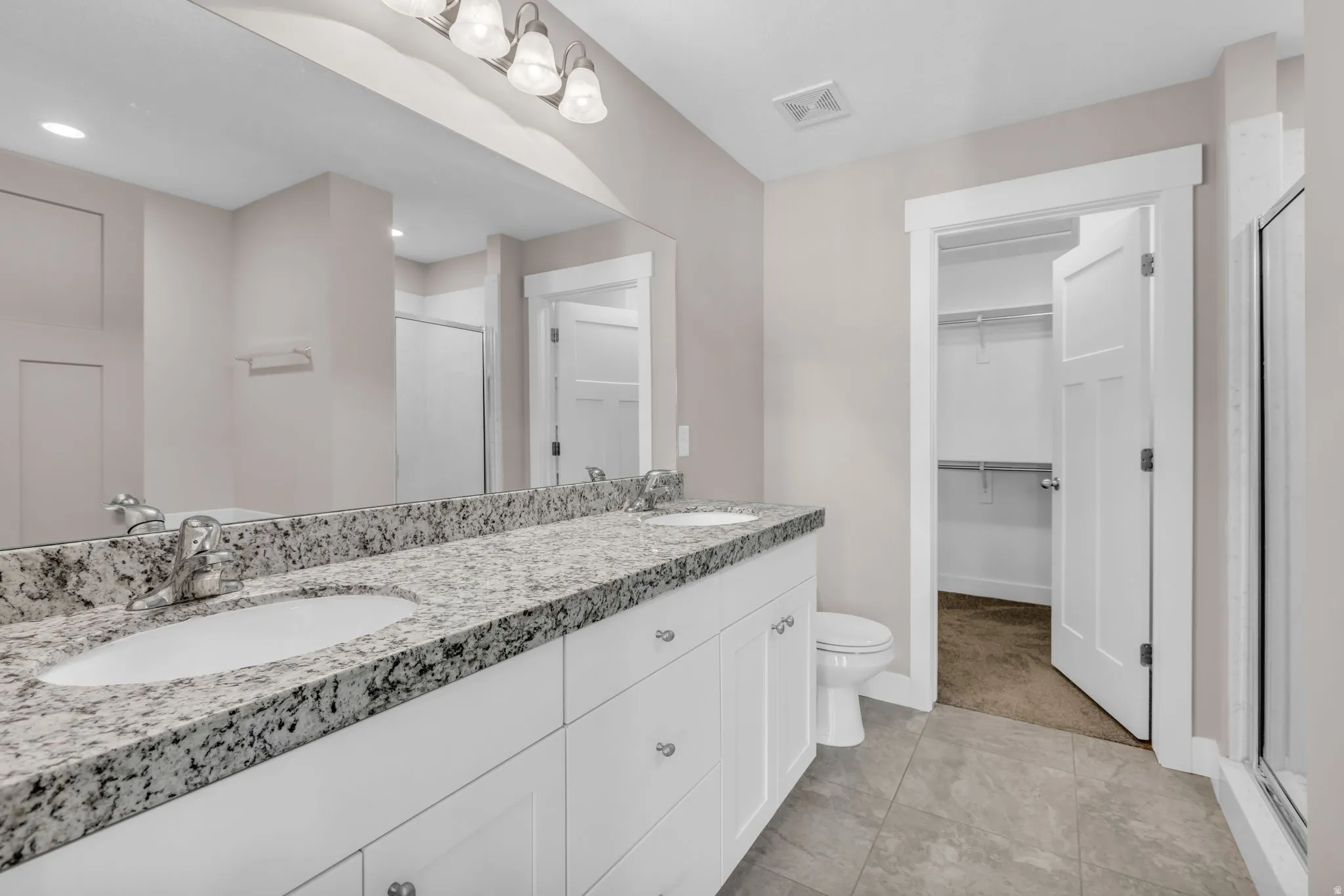 Dual vanity with granite-style countertop, undermount sinks, and white cabinetry
