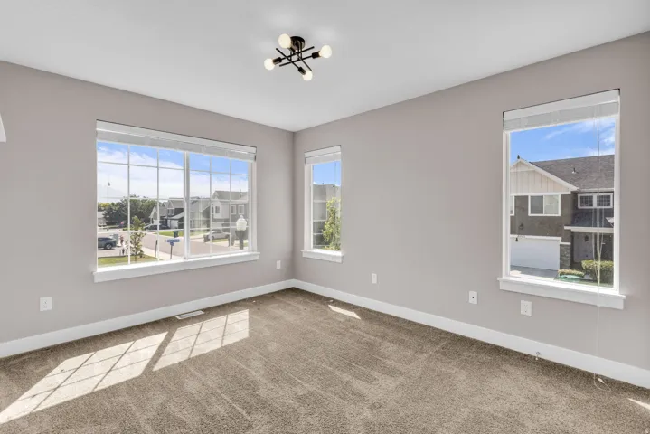 Spacious room featuring multiple windows with white trim, gray painted walls, and textured carpet flooring