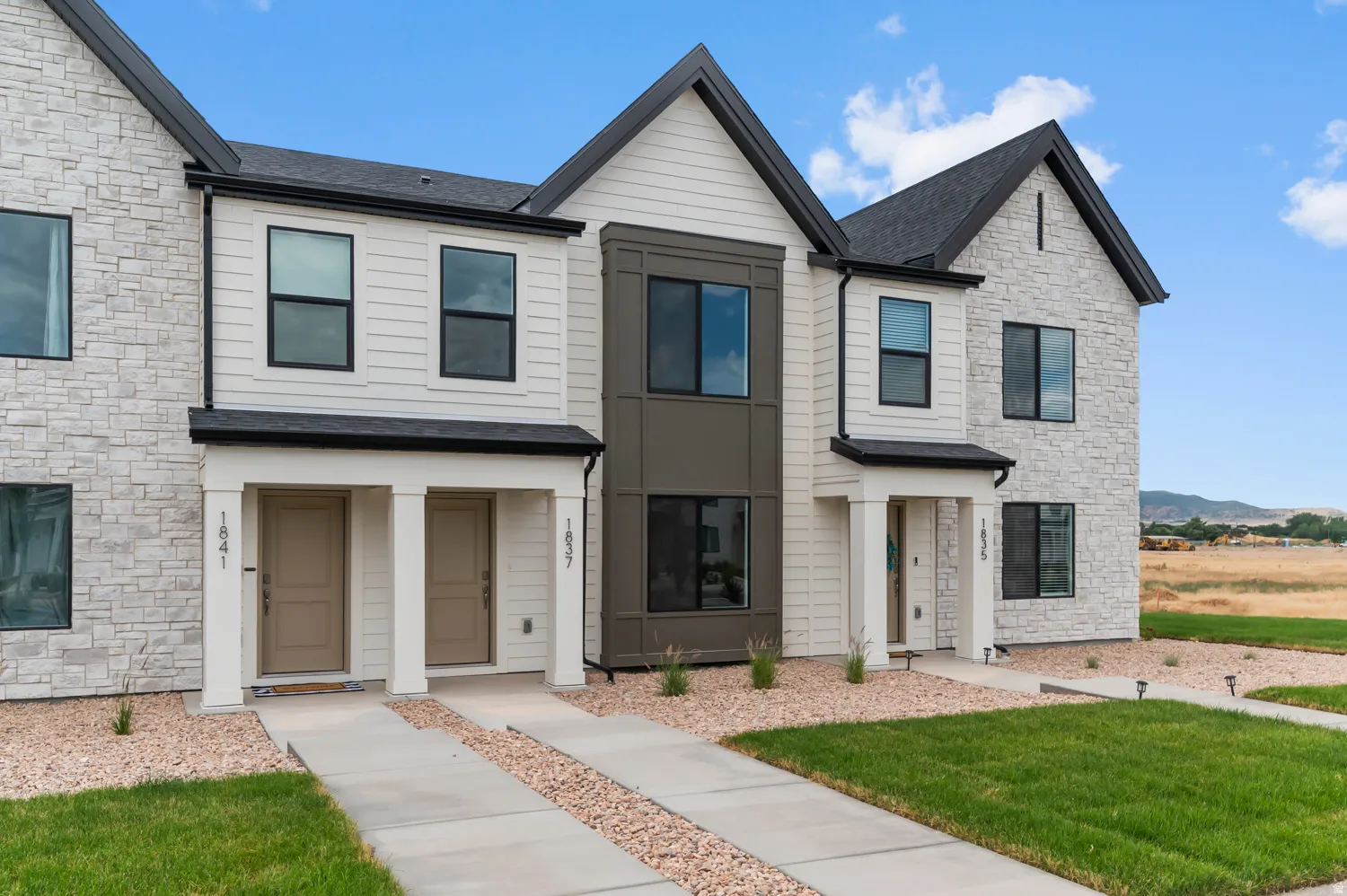 Modern townhome featuring a striking brick and stone exterior with contrasting trim detailing