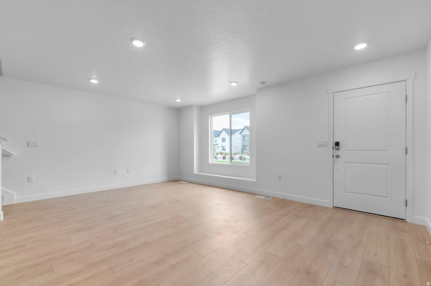 Spacious room featuring wood-finish flooring, recessed lighting, and a large window with white trim