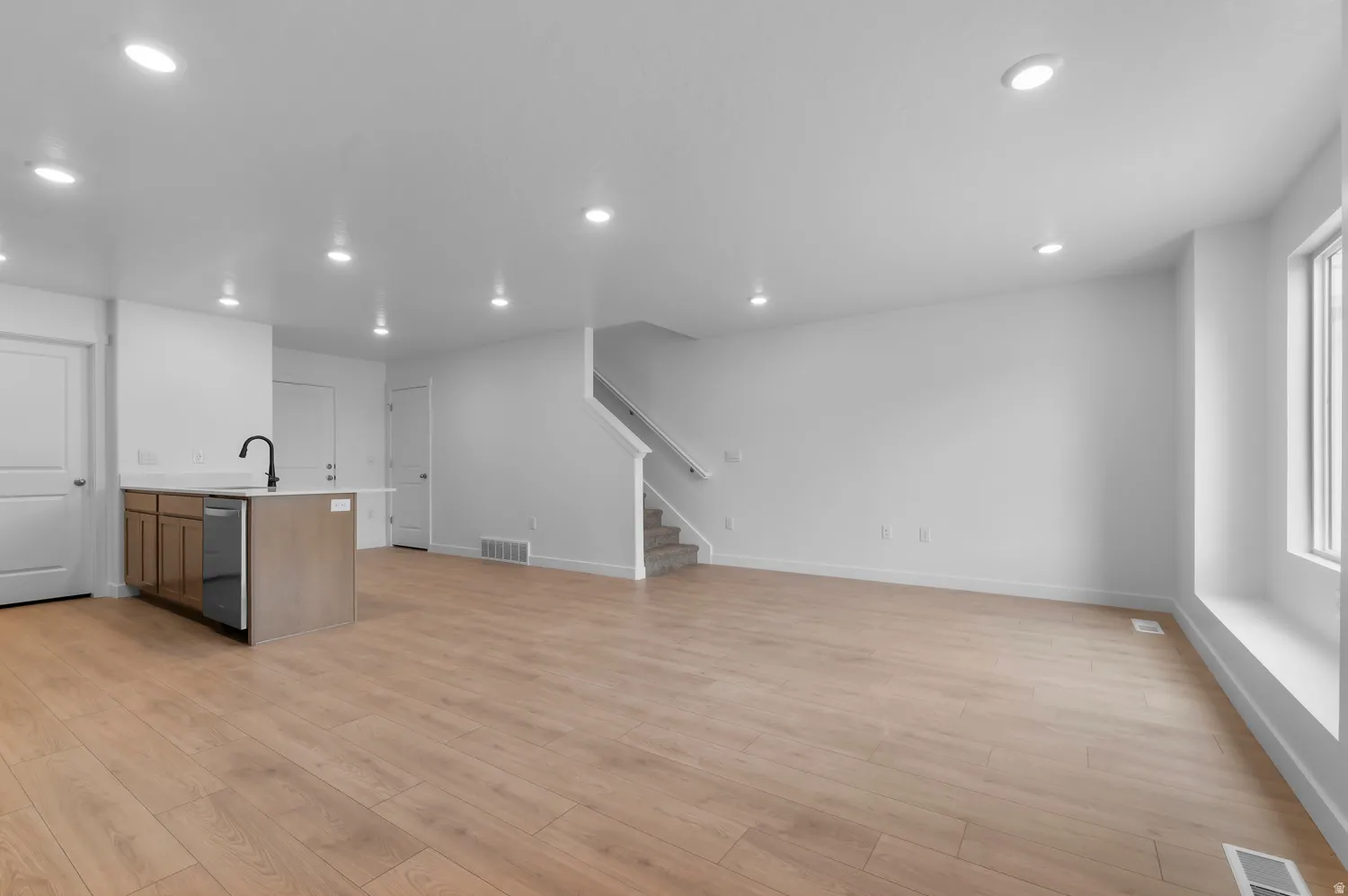 Open-concept living space featuring wood-finish flooring, recessed lighting, and white walls