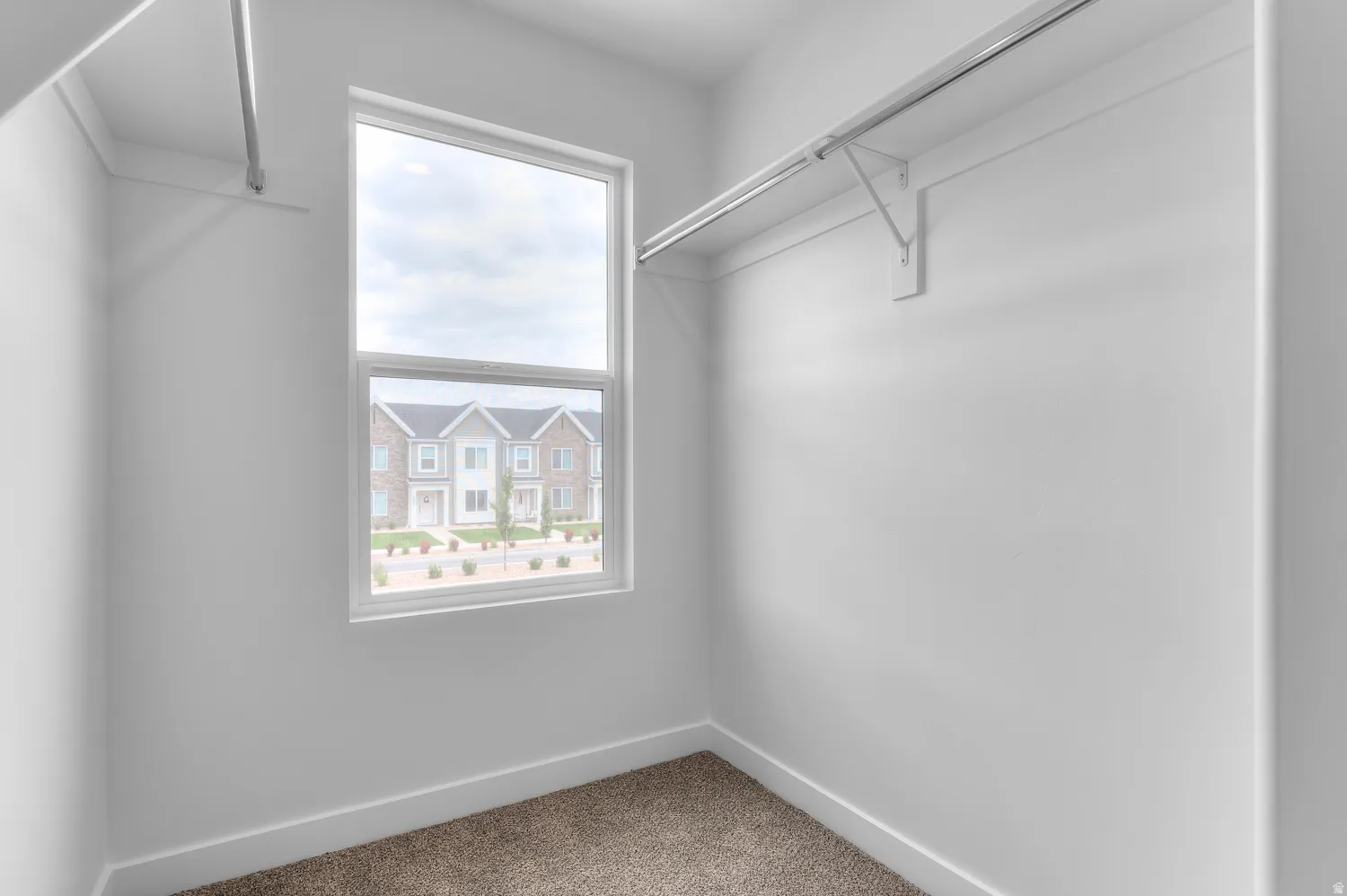 Spacious closet featuring white walls, baseboards, and neutral-toned carpeting