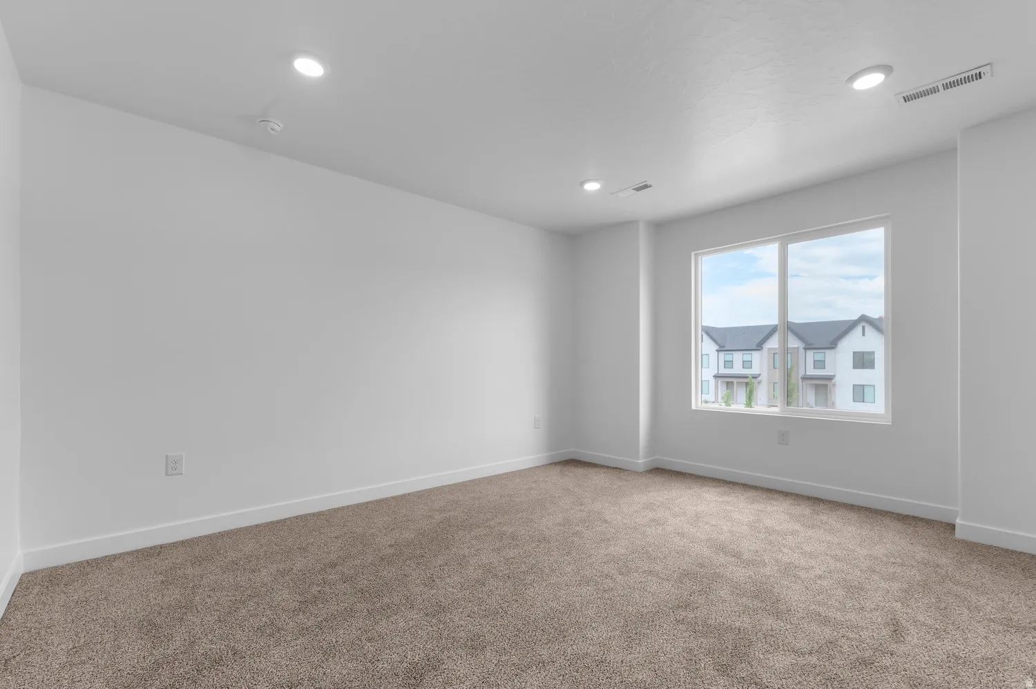 Carpeted room featuring a large window, recessed lighting, and white baseboards