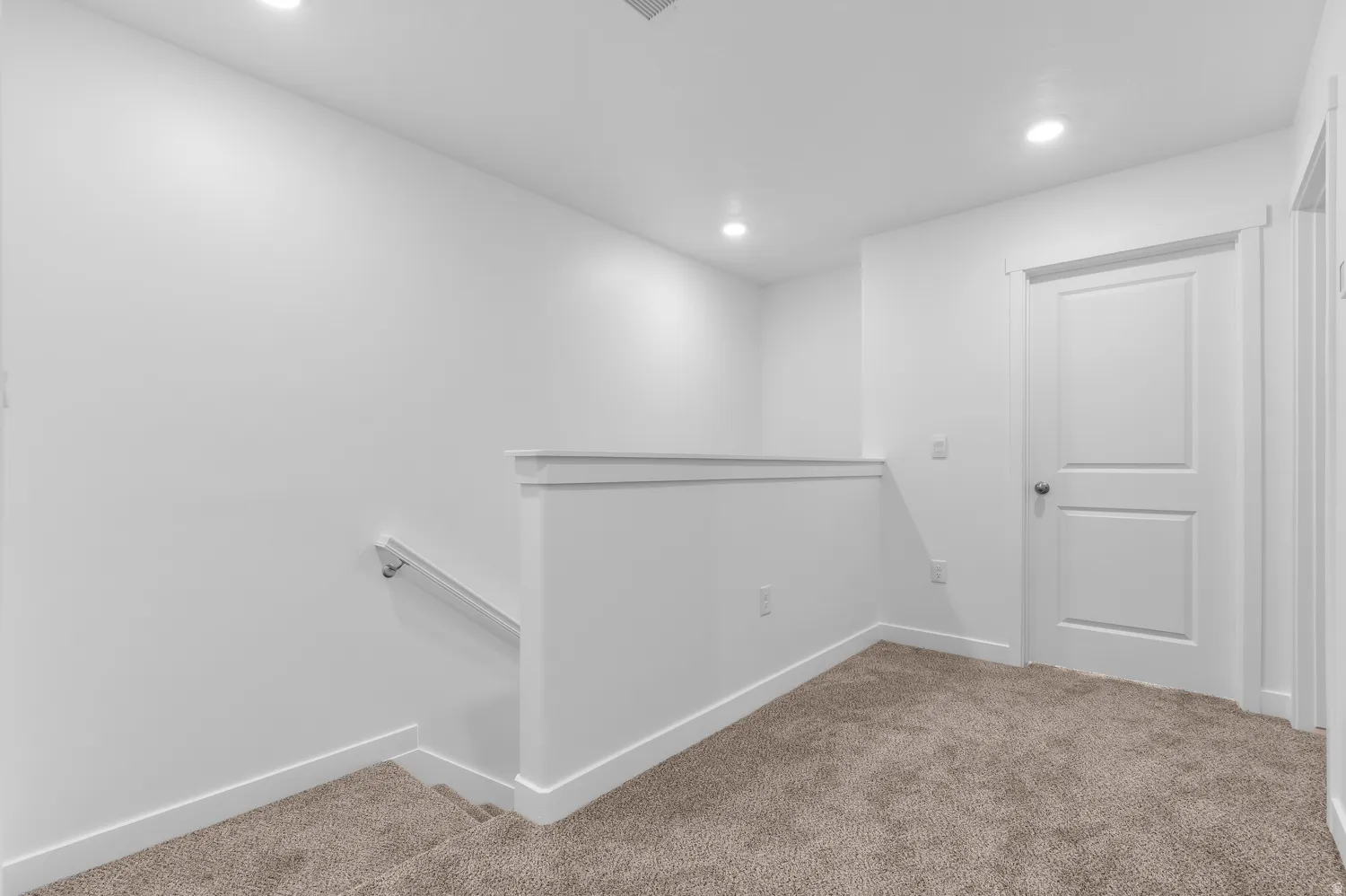 Upper landing featuring recessed lighting, a two-panel interior door, and neutral-toned carpeting