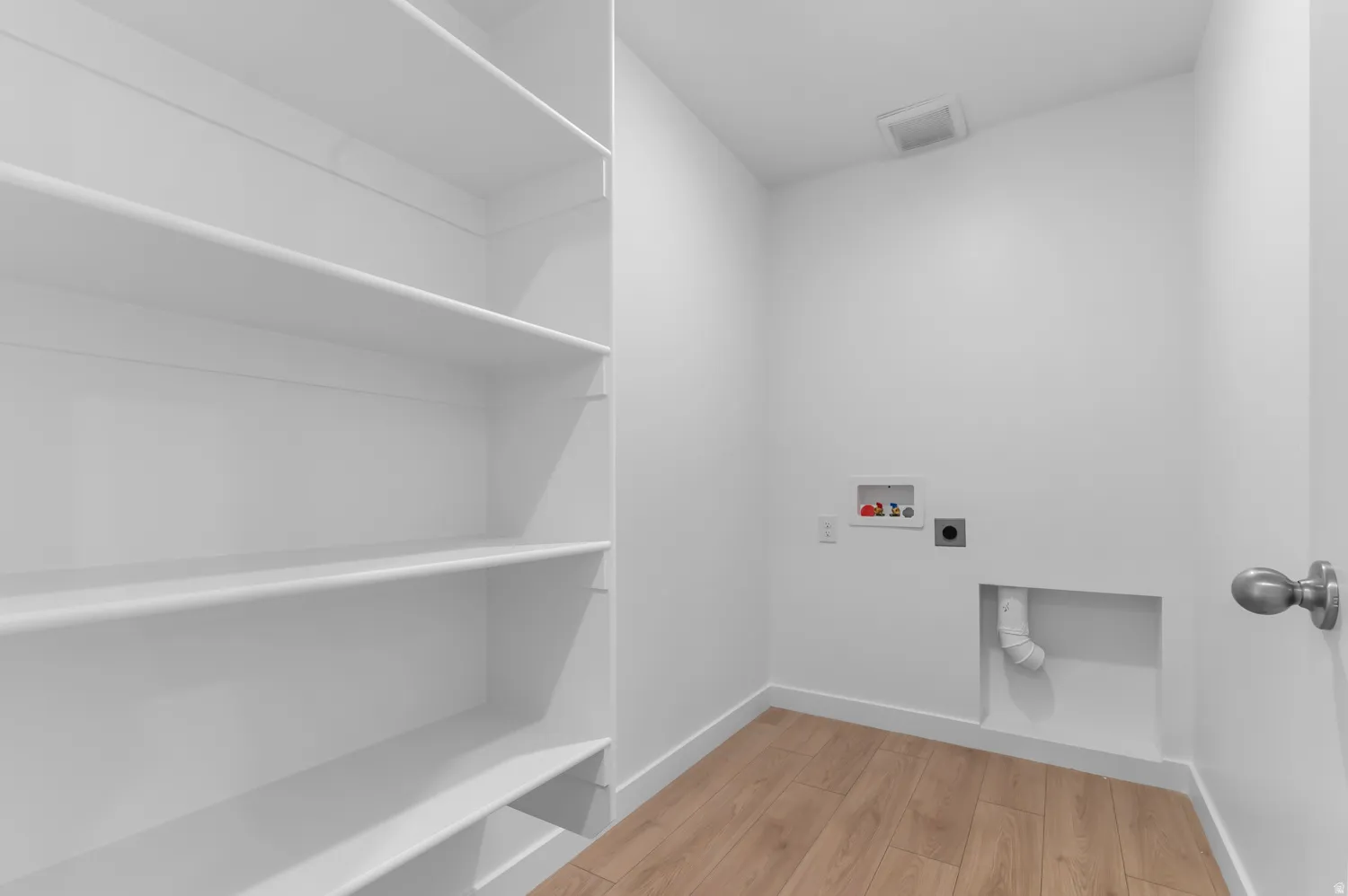 Laundry area featuring white walls, wood-finish flooring, and built-in shelving