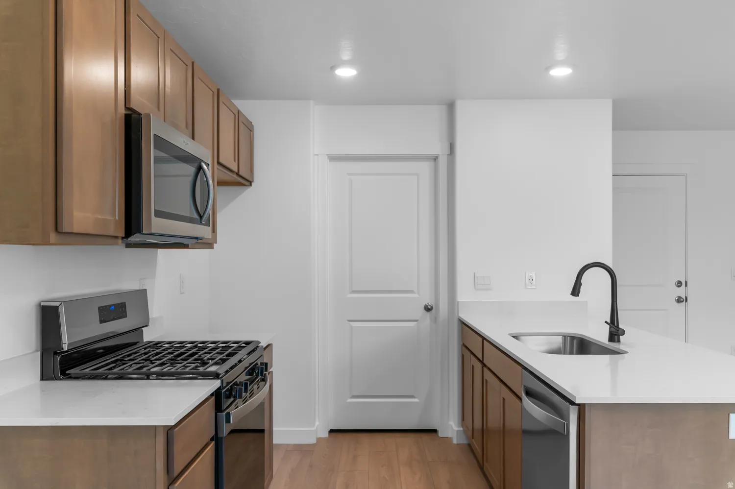 Kitchen featuring stainless steel appliances, wood-finish cabinetry, white countertops, and recessed lighting