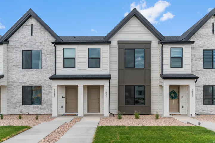 Modern townhome exterior featuring stone veneer, horizontal siding, black-framed windows, and a covered entry