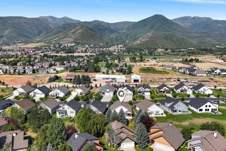 Established residential community nestled in a verdant valley, featuring multiple single-family homes with contemporary architectural styling, dark composition roofing, and manicured landscaping