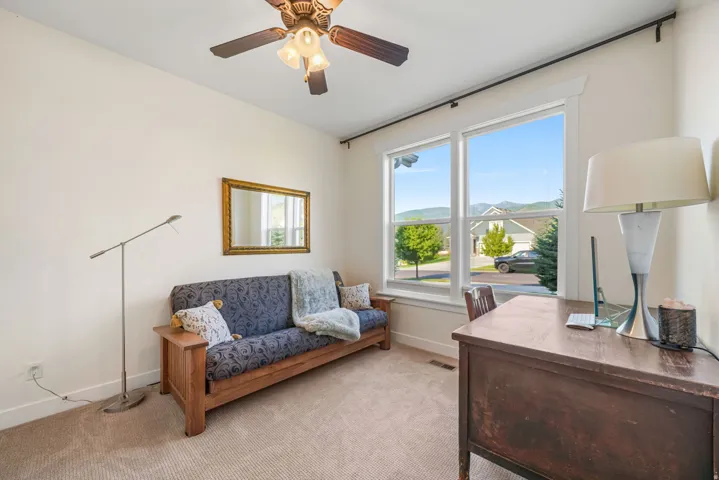 Bright room featuring a large window, neutral carpet flooring, and a ceiling fan with integrated lighting