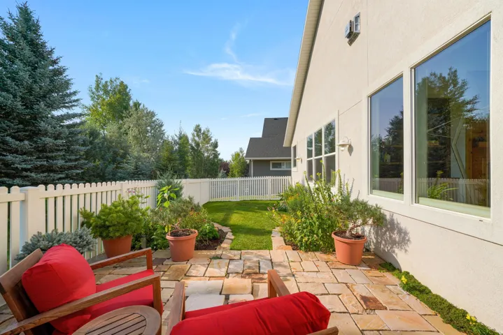 Stone patio with a white picket fence and surrounding greenery