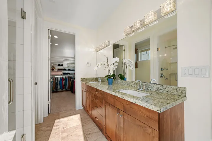 Dual vanity with a stone countertop, under-mount sinks, and a large mirror