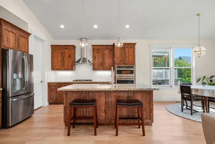 Kitchen featuring warm wood cabinetry, light wood-finish flooring, and granite countertops
