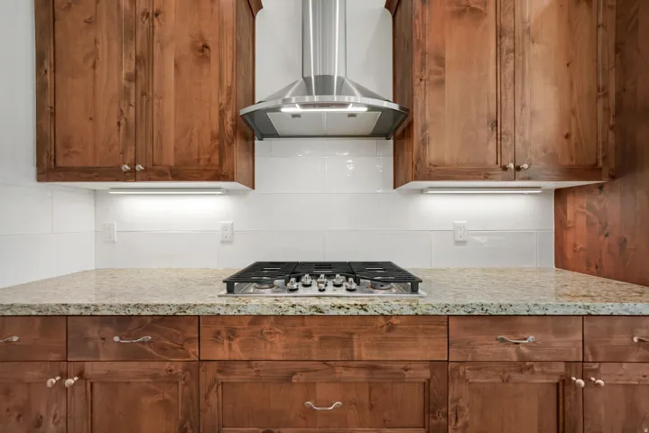 Kitchen featuring wood cabinetry, light-toned countertop, and white tile backsplash
