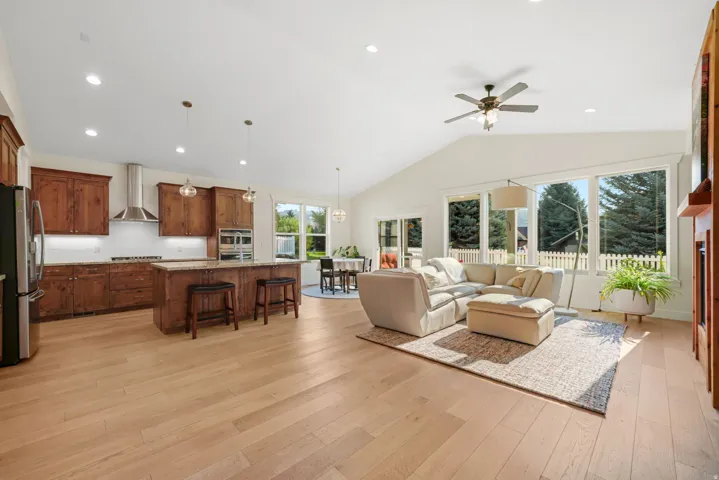 Expansive open-concept living space with wood-finish flooring, vaulted ceilings, and recessed lighting