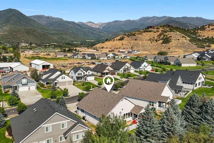 Residential property with a light-colored roof and an attached garage, situated in a community featuring varied home styles, manicured lawns, and mature landscaping