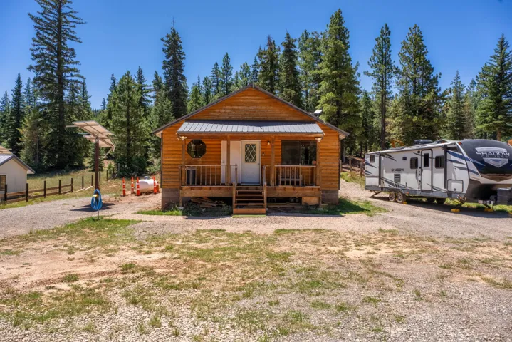 Log cabin exterior featuring a covered porch with wood railings and steps