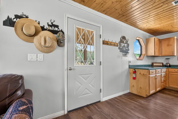 Wood-finish flooring throughout, complemented by light gray paneled walls and a natural wood plank ceiling