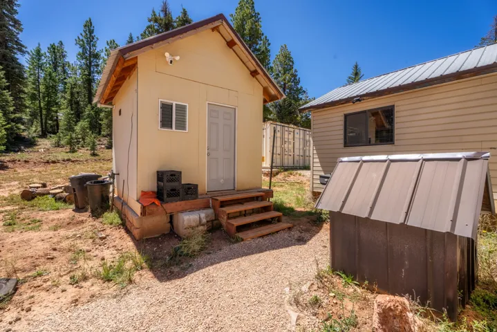 Compact structure with neutral siding, a single entry door, and a louvered window