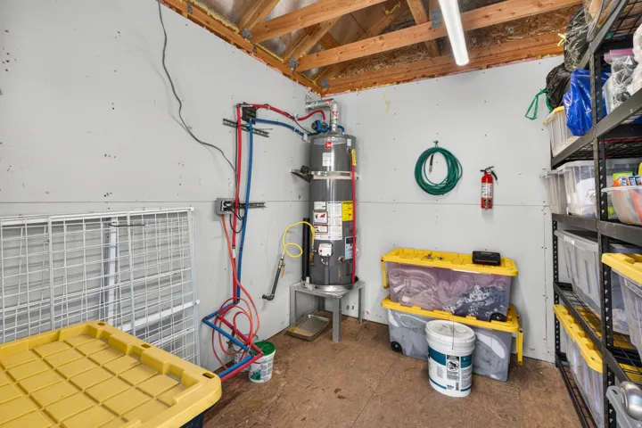 Utility space featuring exposed wood framing, white paneling, and a floor-mounted water heater