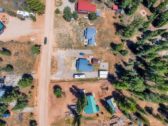 Aerial perspective showcasing properties along a dirt road with mature trees and varied landscaping