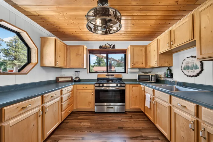 Kitchen featuring a wood-finish plank ceiling, light wood cabinetry, dark countertops, and wood-finish flooring