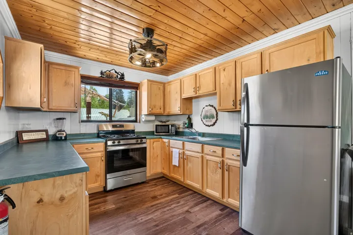 Kitchen featuring wood-finish flooring, natural wood cabinetry, stainless steel appliances, and a wood-plank ceiling