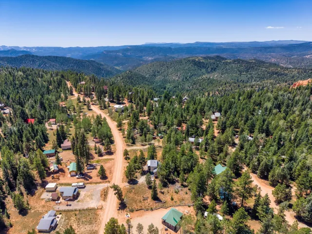 Expansive aerial perspective showcasing a mountainous, wooded landscape with scattered properties