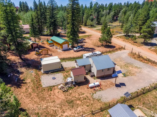 Property featuring a main residence with a metal roof, several outbuildings, and solar panel installations