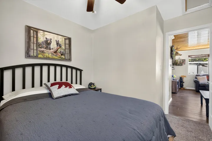 Bedroom featuring light neutral wall paint, a dark-toned headboard, and a ceiling fan with wood-finish blades