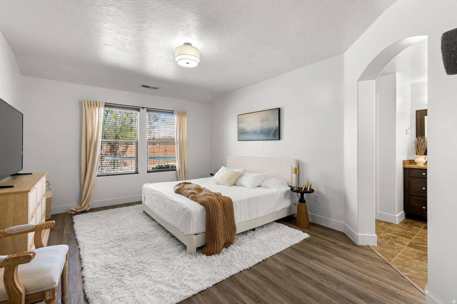 Interior room featuring wood-finish flooring, white walls, and a recessed window with blinds