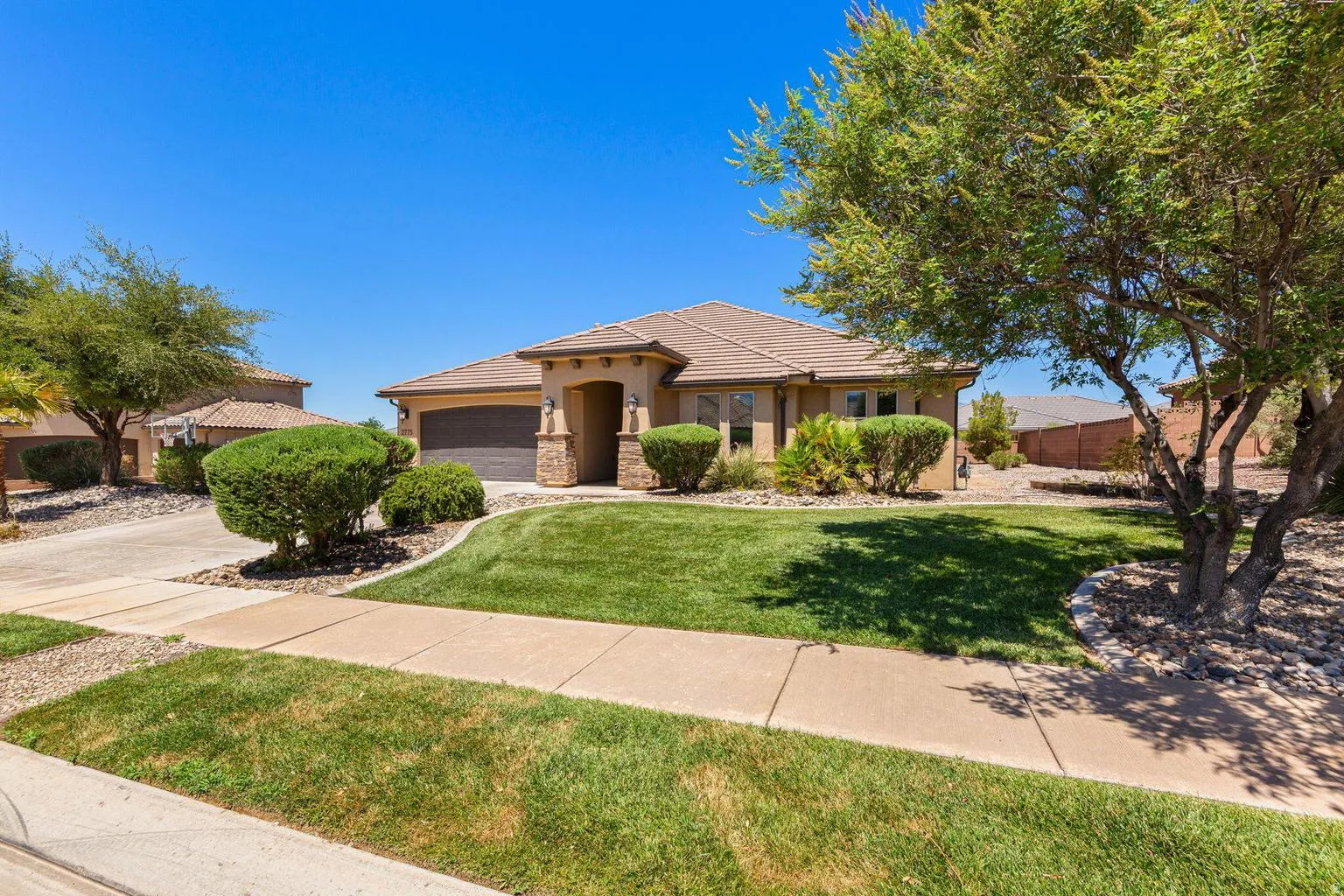 Single-story residence featuring a stucco exterior with a tile roof, an integrated two-car garage, and a covered entry