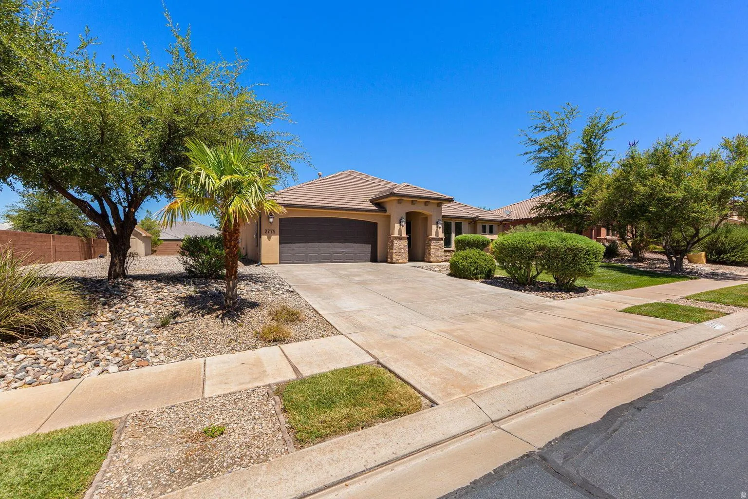 Stucco exterior featuring a tile roof and an attached garage with a dark wood-finish door