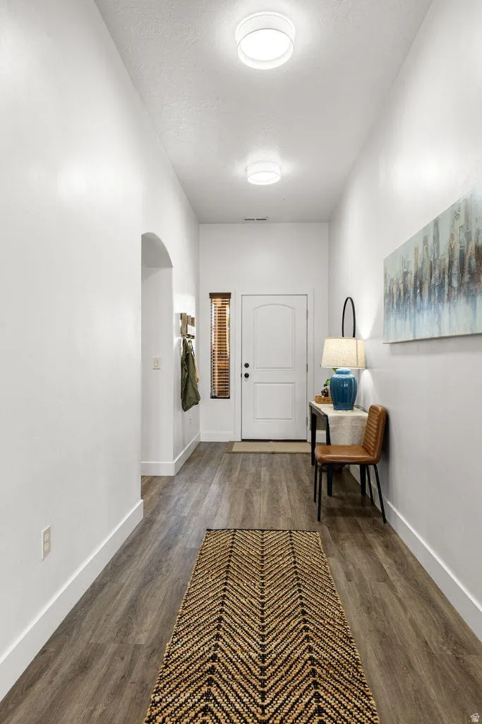 Hallway featuring wood-finish flooring, white baseboards, and bright overhead lighting