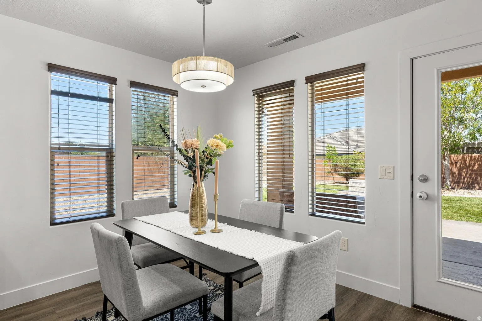 Dining area featuring wood-finish flooring and a contemporary drum pendant light fixture