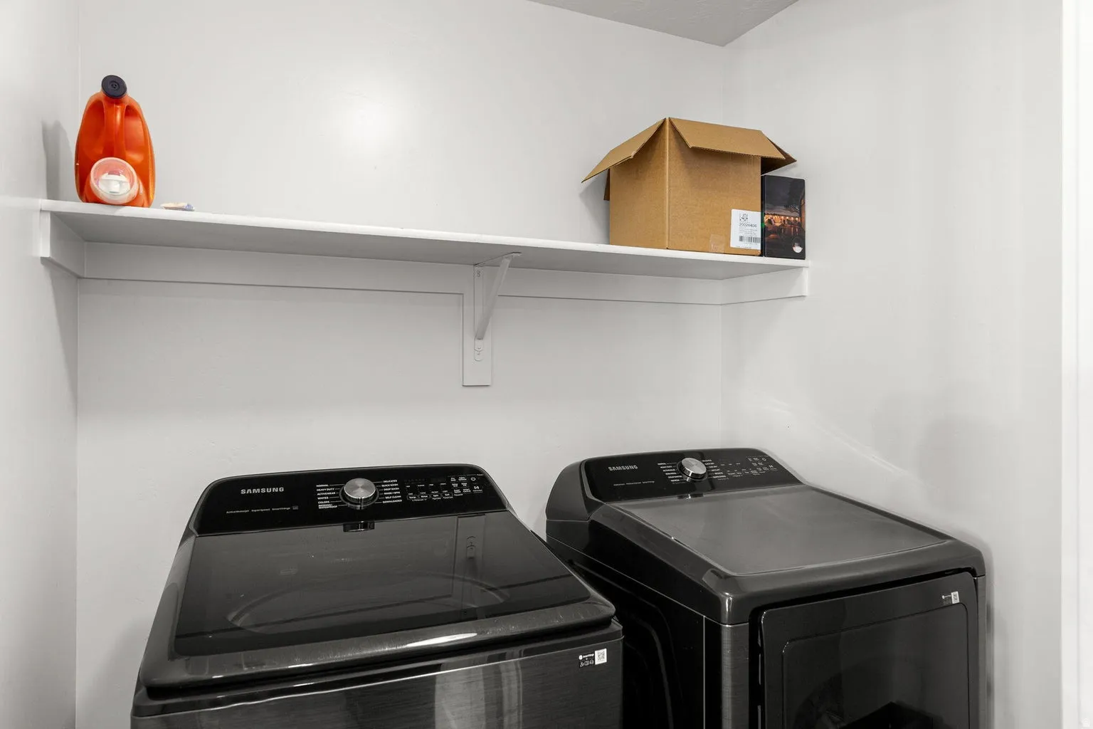 Dedicated laundry space with white walls and built-in shelving