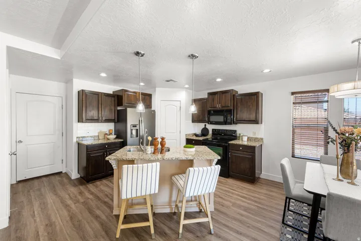 Kitchen featuring dark wood cabinetry, granite countertops, and a subway tile backsplash