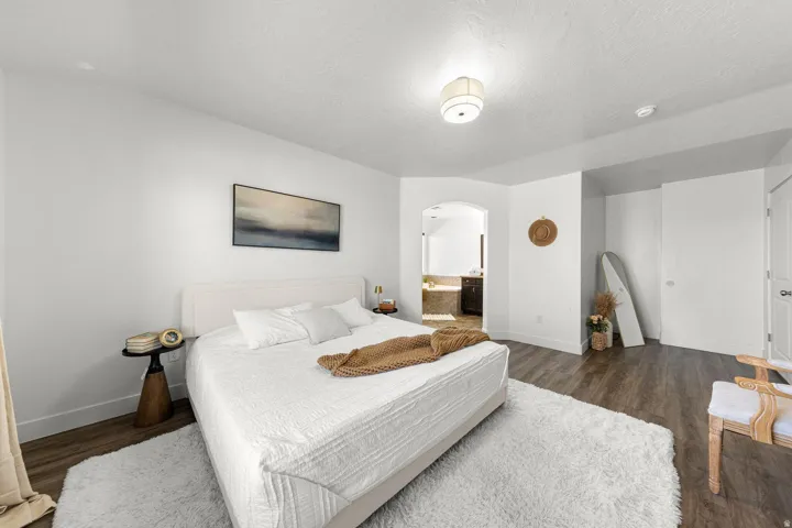 Spacious bedroom featuring wood-finish flooring, white walls, and a ceiling-mounted light fixture