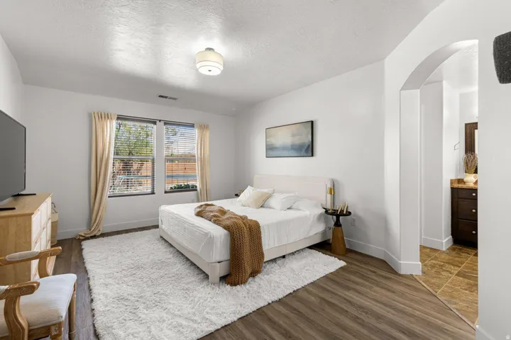 Interior room featuring wood-finish flooring, white walls, and a recessed window with blinds