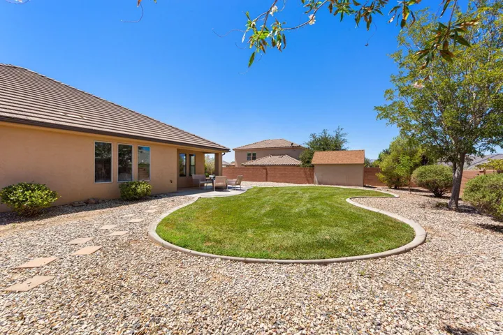 Expansive rear yard featuring a curved lawn area, gravel landscaping, and a covered patio